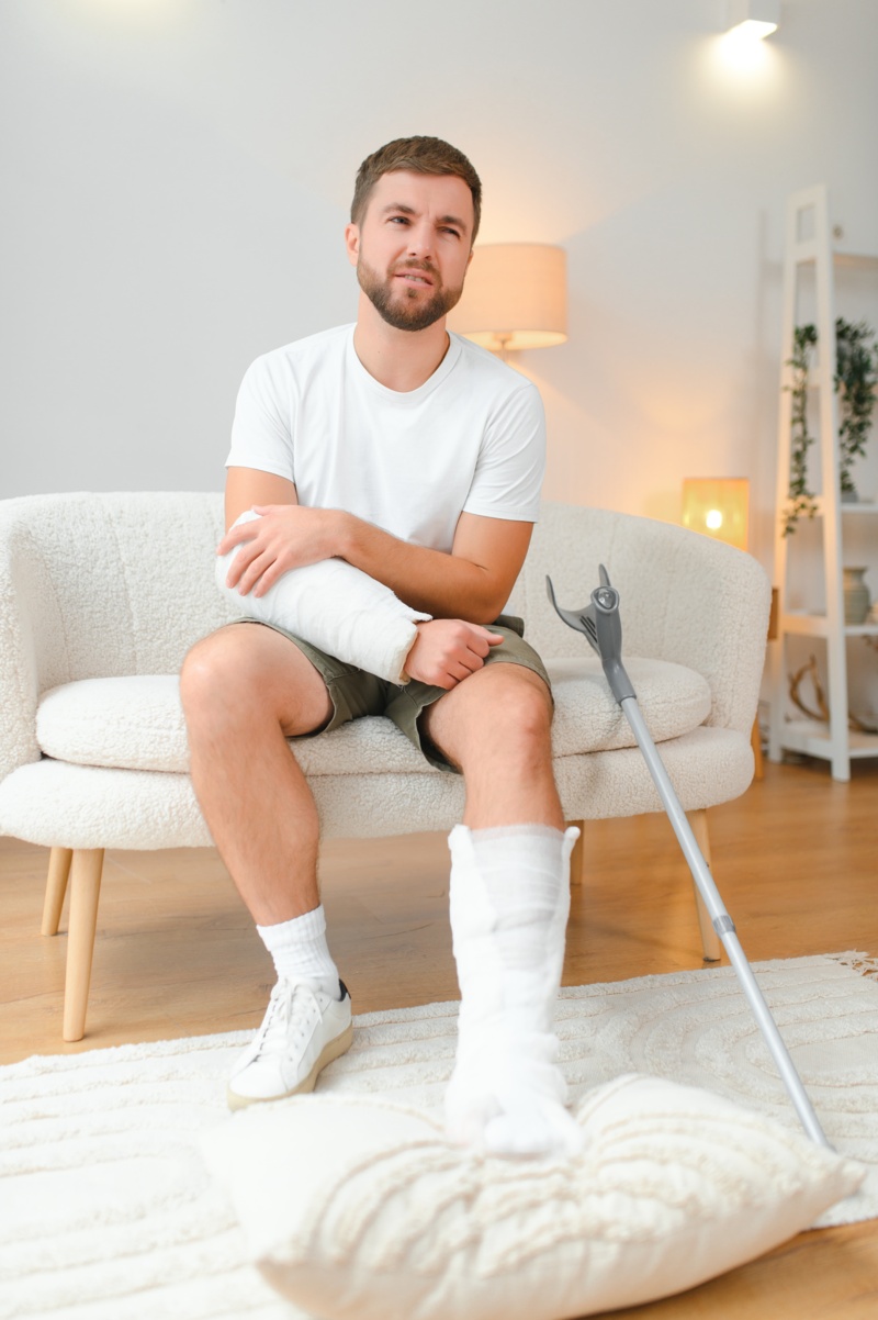 recovery-after-physical-injury-accident-home-sad-unlucky-young-man-with-broken-leg-injured-arm